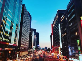 Traffic on city street by buildings against sky