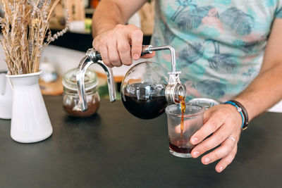 Midsection of woman holding wineglass on table