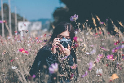 Portrait of woman photographing with flowers