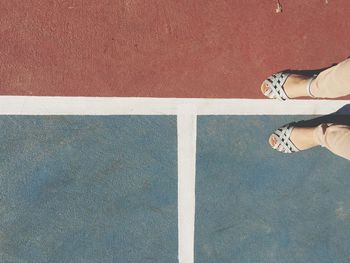 Low section of woman standing at tennis court