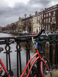 Bicycles by river against buildings in city