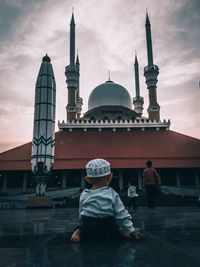 Rear view of people outside building against sky