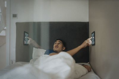 Boy adjusting temperature of bedroom through digital tablet at modern home