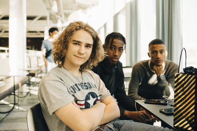 Portrait of confident male friends sitting in restaurant at shopping mall