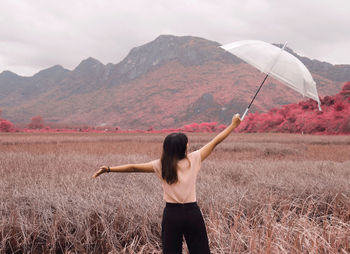 Woman standing on field against mountain range