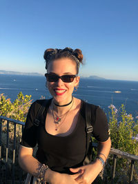 Portrait of smiling woman wearing sunglasses against sea