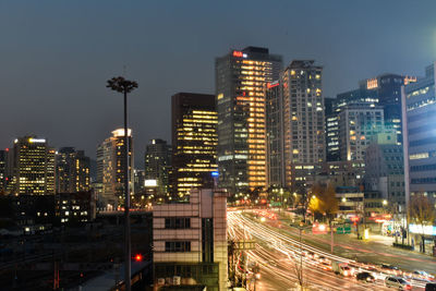Illuminated buildings in city against sky at night