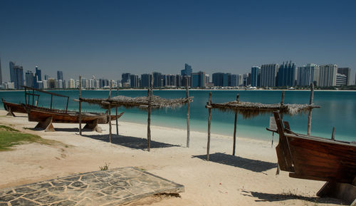 Boats moored on sea by city against clear sky