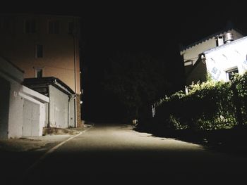 Empty road amidst buildings in city at night