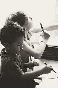 High angle view of friends writing on paper at table