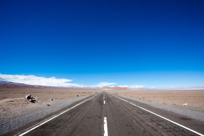 Road amidst desert against blue sky