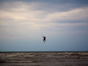 Person kiteboarding over sea against sky