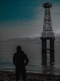 Rear view of man standing by sea against sky
