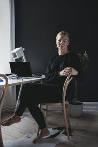 Portrait of businesswoman sitting on chair by desk in home office