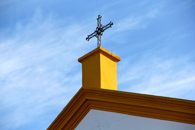 Low angle view of weather vane against building