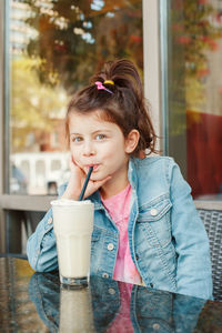 Portrait of cute girl drinking milk at cafe