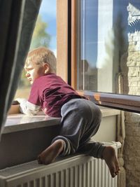 Boy looking through window at home