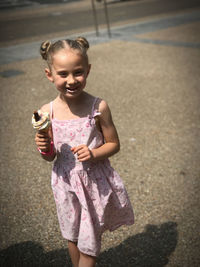 Cute girl standing outdoors eating ice cream