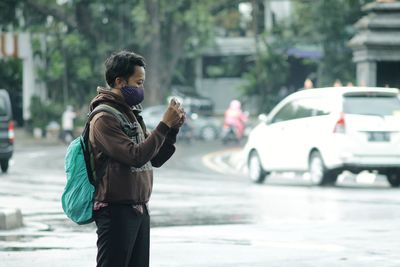 A man with a mask taking a photo against a traffic background