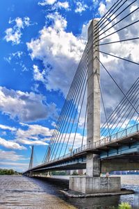 Low angle view of suspension bridge against cloudy sky