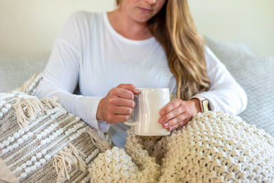 Midsection of woman holding coffee cup at home