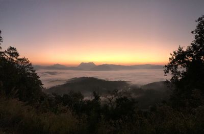 Scenic view of silhouette mountains against orange sky