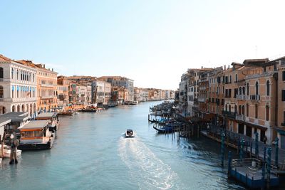 Boats in canal amidst buildings against sky