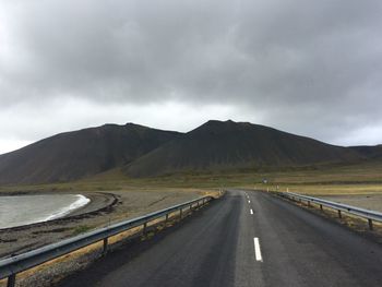 Road leading towards mountains against sky