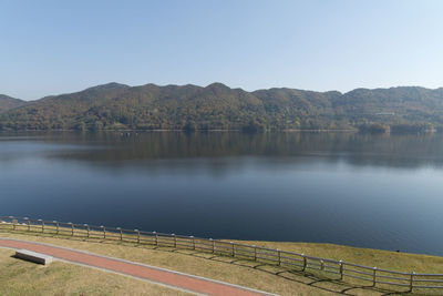 Scenic view of river by mountains against clear sky