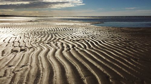 View of calm beach against cloudy sky