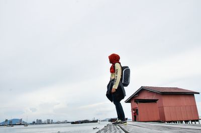 Woman standing on pier by lake against sky