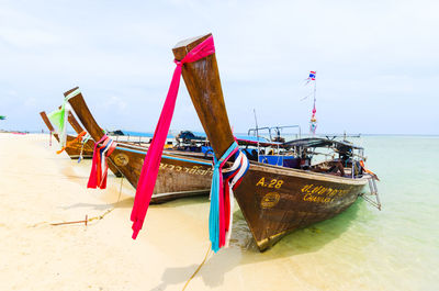 Fishing boats moored on beach against sky