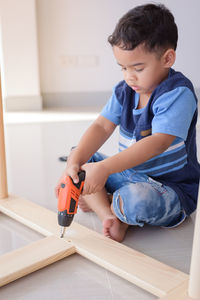 Boy drilling wood at home