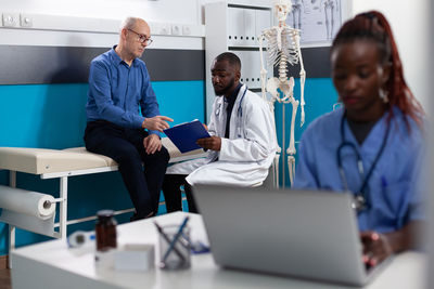 Midsection of doctor explaining to patient in office