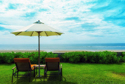 Deck chairs on beach against sky