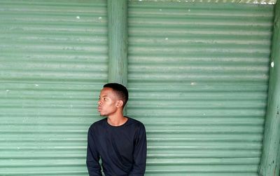 Close-up of man against green corrugated iron