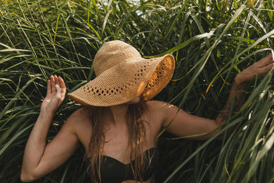 Young woman wearing hat while standing against plants
