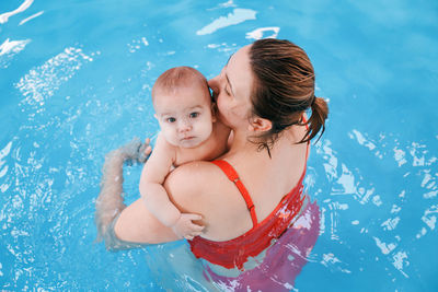 Woman holding baby boy in swimming pool