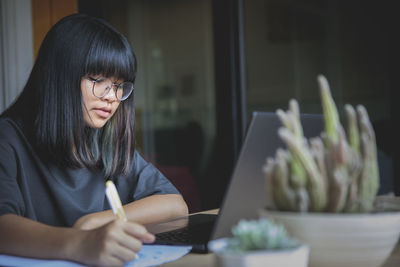 Young woman using phone while sitting on table