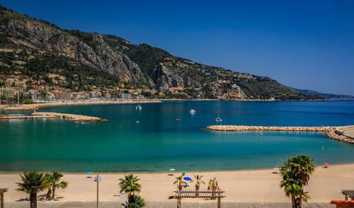 Scenic view of sea and mountains against blue sky