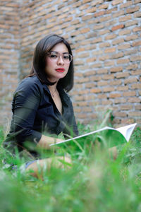 Portrait of beautiful young woman against wall