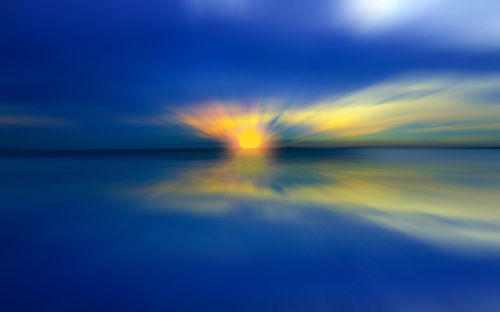 Defocused image of sea against sky during sunset