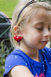 Close-up of cute girl with cherry on ear