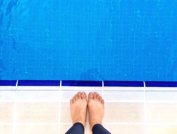 Low section of man standing by swimming pool