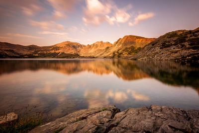 Scenic view of lake by mountains against sky during sunset