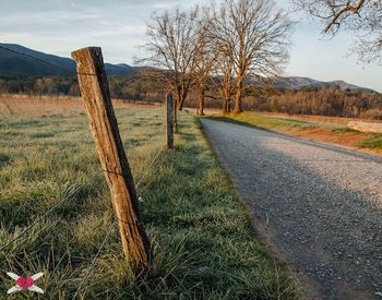 Empty road by fence on grassy field