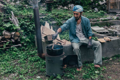 Man cooking while sitting outdoors