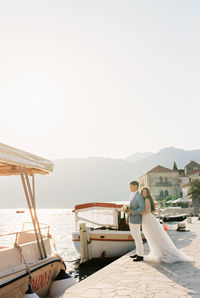 Rear view of man sitting on pier against clear sky