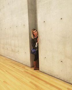 Portrait of young woman standing amidst wall