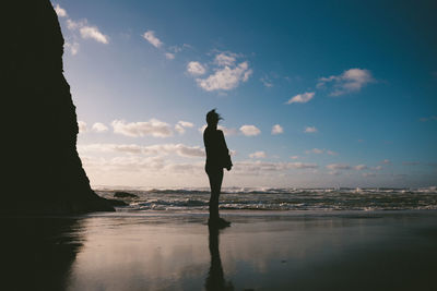 Silhouette man standing on beach against sky